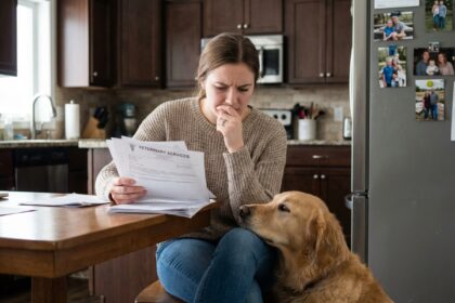 Femme et chien regardant des factures vétérinaires à la maison